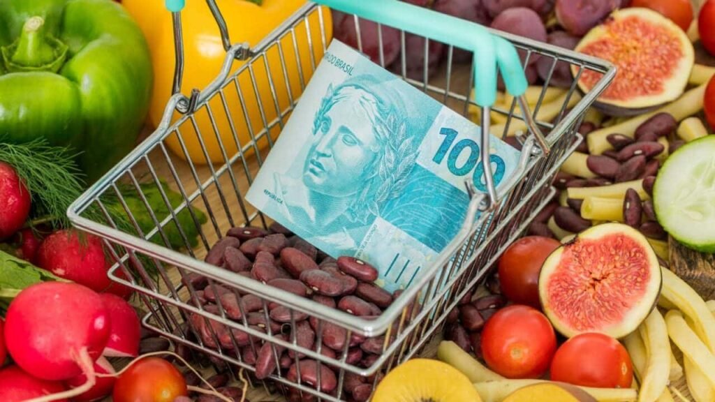 Alimentos com uma cesta contendo uma nota de 100 reais